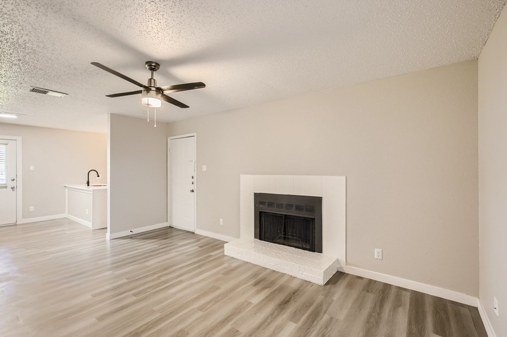 A living room with a fireplace and a ceiling fan.
