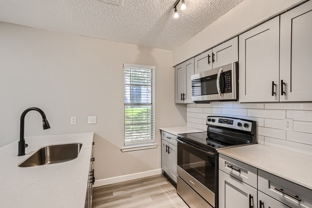 A kitchen with a stove, oven, and microwave.