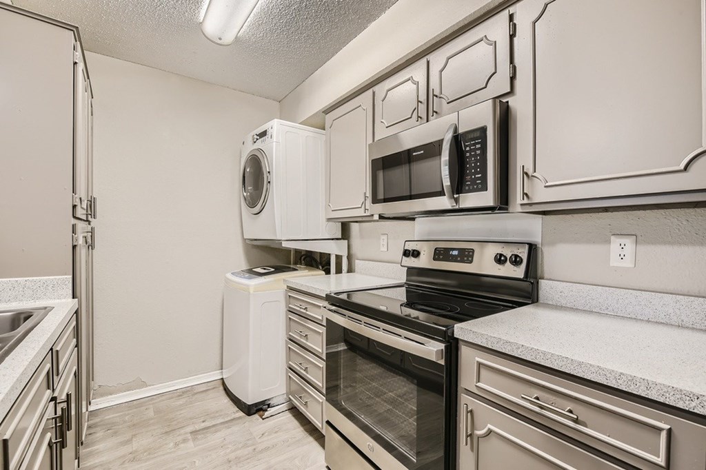 A kitchen with a white fridge, microwave, oven, and dishwasher.