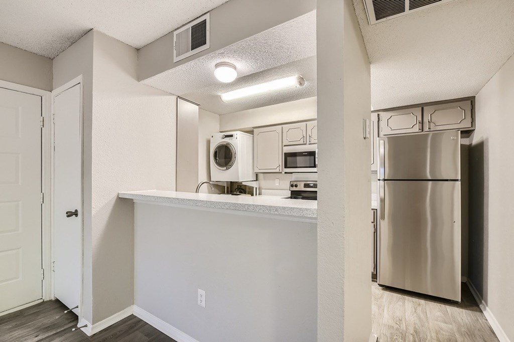 A kitchen with a white counter and a stainless steel refrigerator.