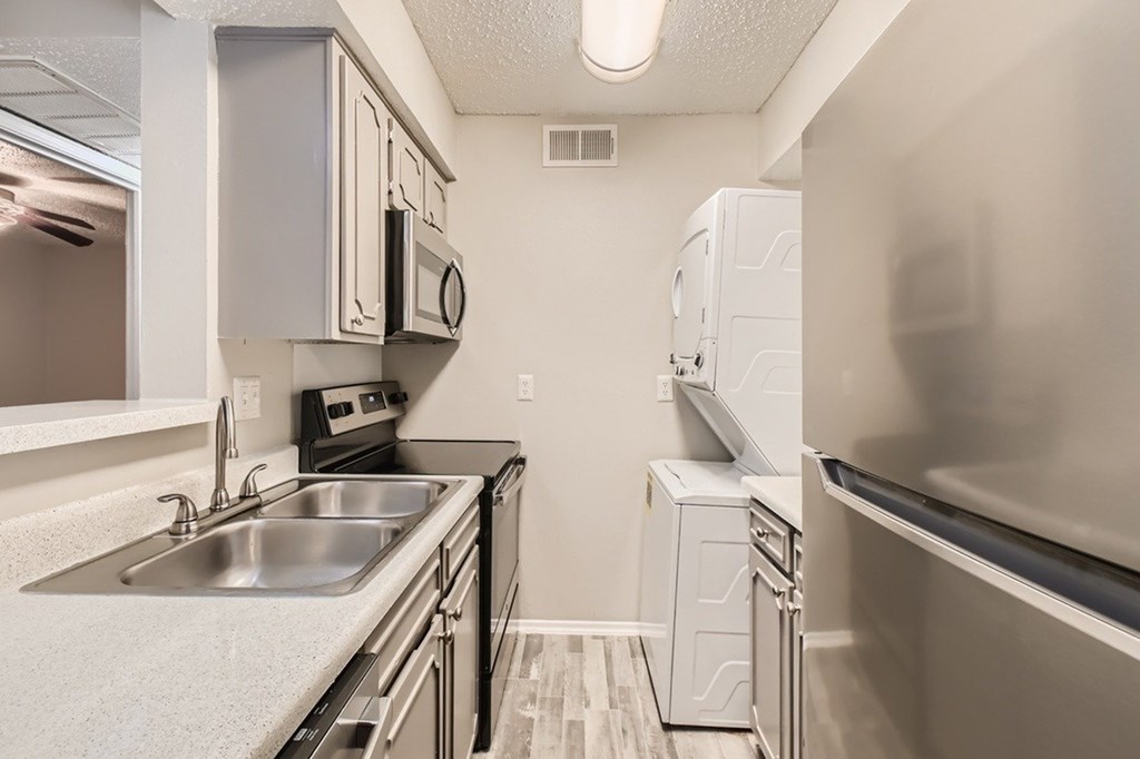 A kitchen with a stainless steel sink and refrigerator.