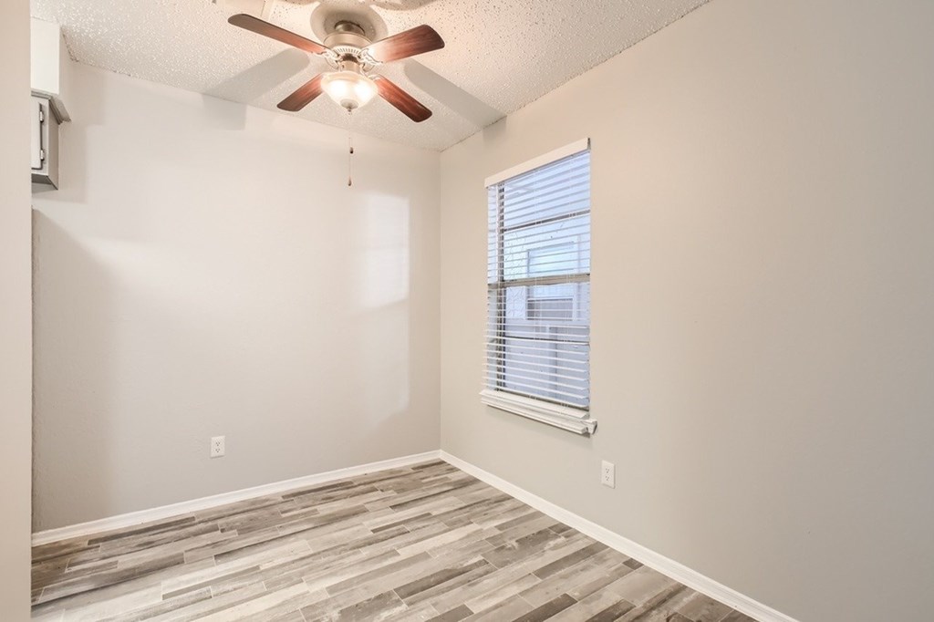 A room with a ceiling fan and a window with blinds.