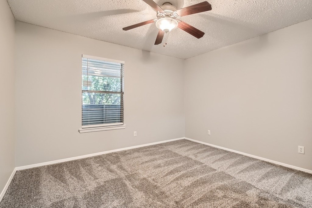 A room with a ceiling fan and a window with blinds.