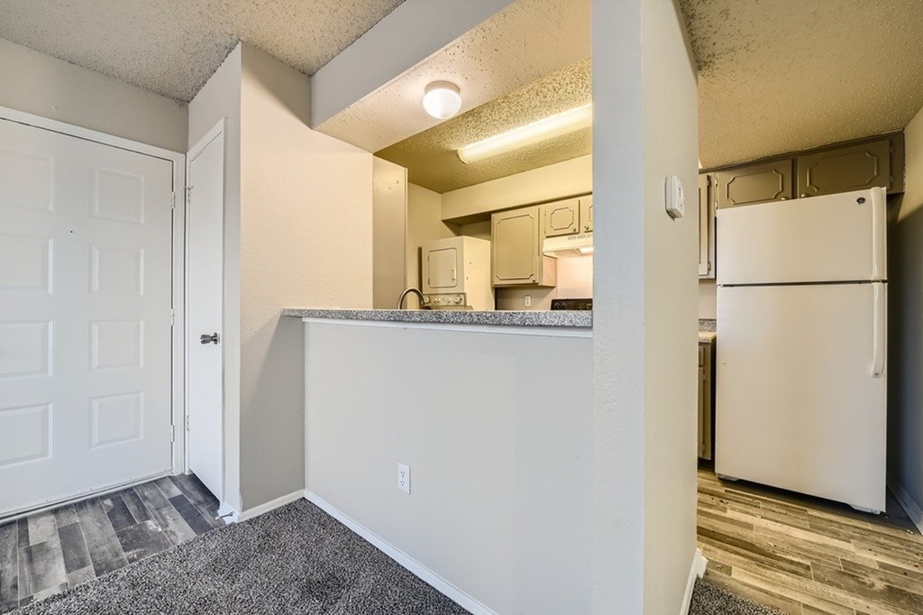 A kitchen area with a white refrigerator and a white door.