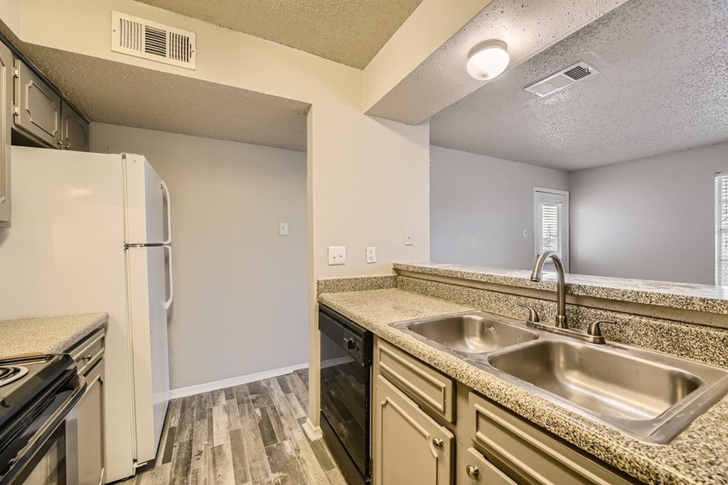 A kitchen with a sink, stove, and refrigerator.