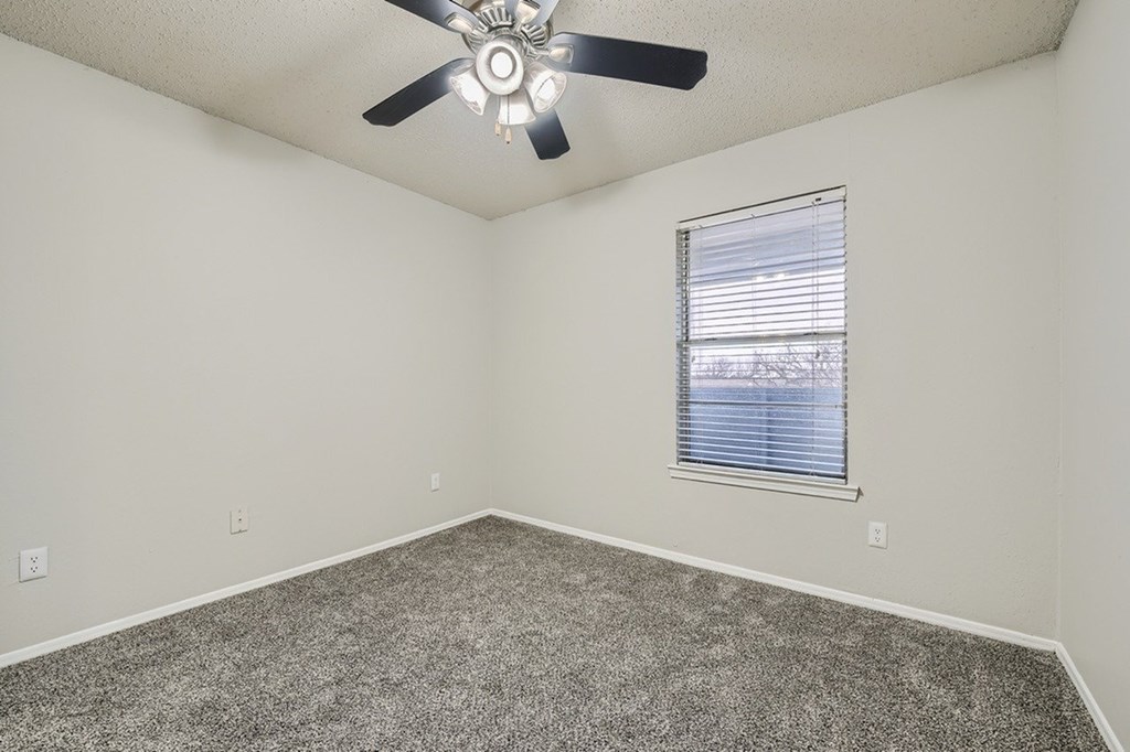 A room with a ceiling fan and a window with blinds.
