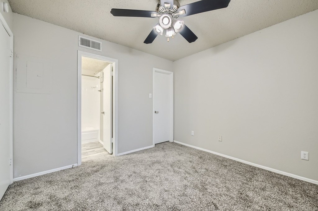A room with a ceiling fan and carpeted floor.