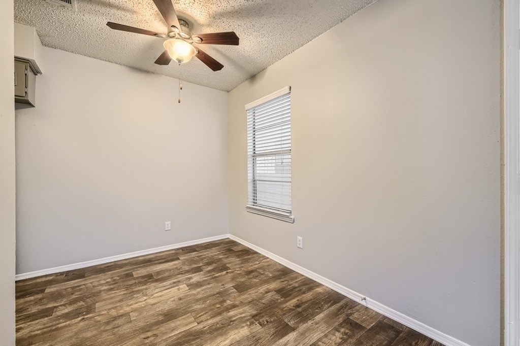 A room with a ceiling fan and wooden flooring.
