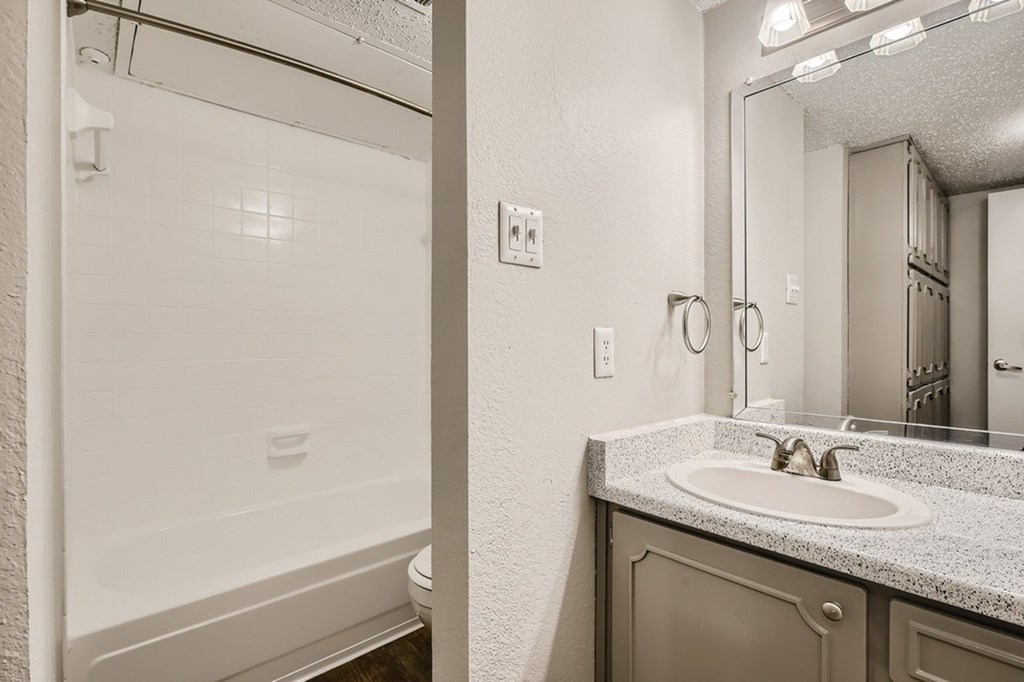 A bathroom with a sink, mirror, and shower.