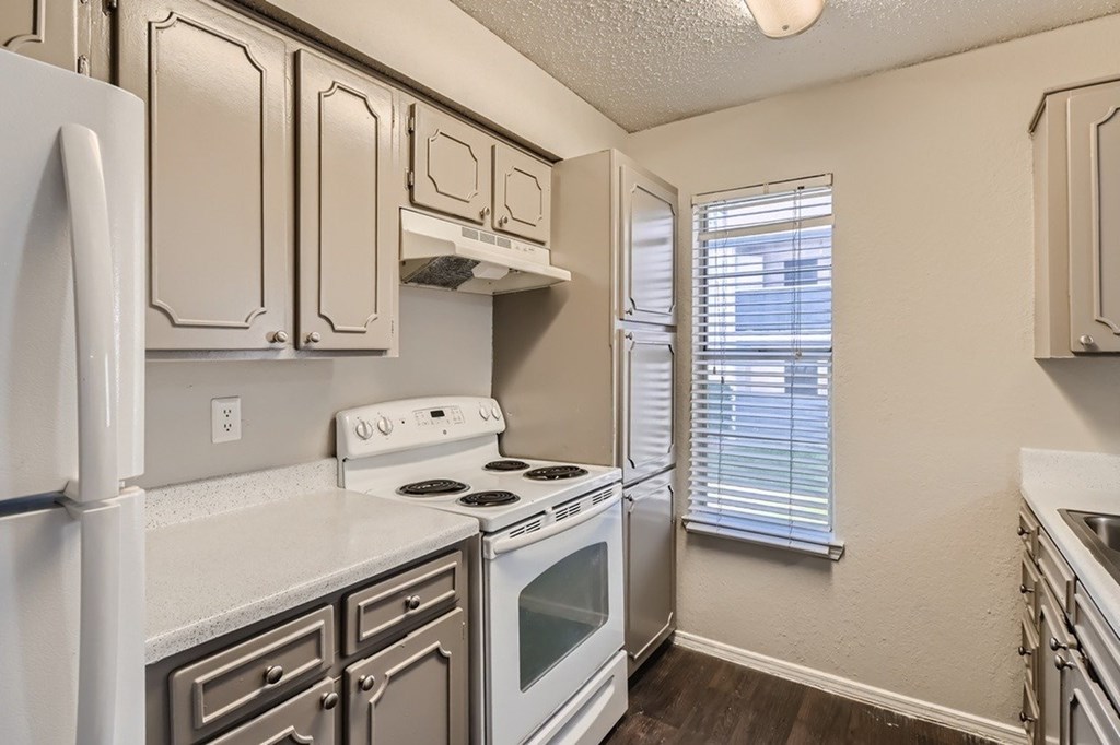 A kitchen with white appliances and wooden floors.