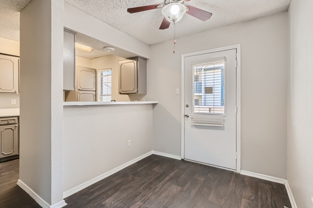 A room with a white door and a ceiling fan.
