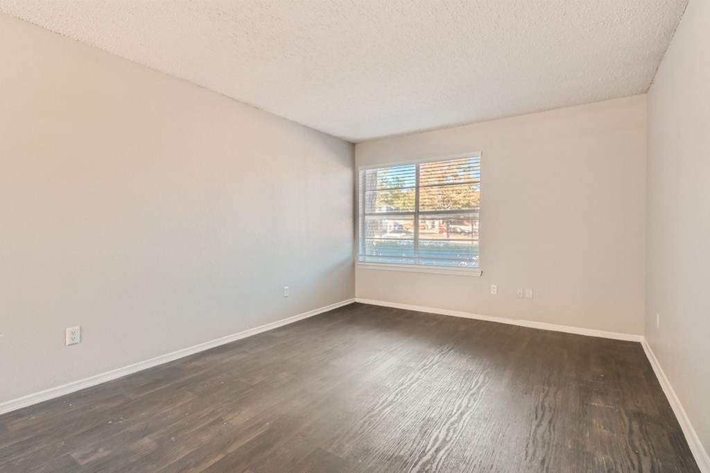 Empty room with wooden flooring and a window.