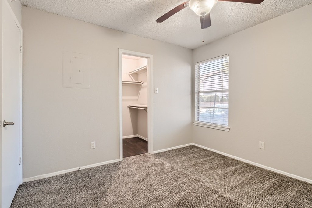 A room with a ceiling fan and a window with blinds.