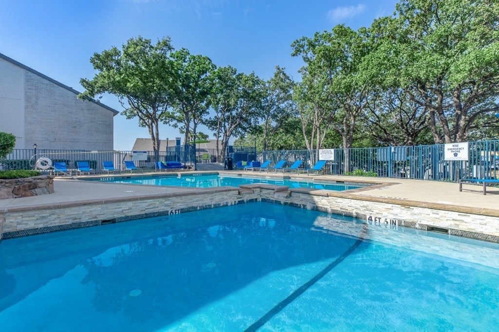 A large outdoor swimming pool surrounded by trees.