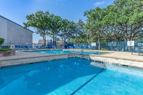 A large outdoor swimming pool surrounded by trees.