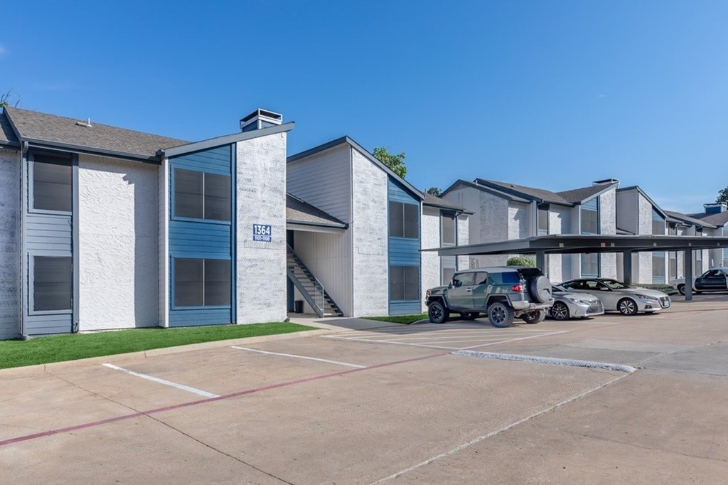 A parking lot in front of a building with cars parked.