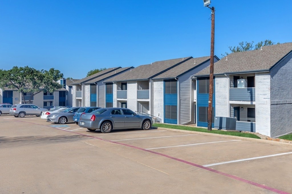 A parking lot with cars and apartment buildings in the background.