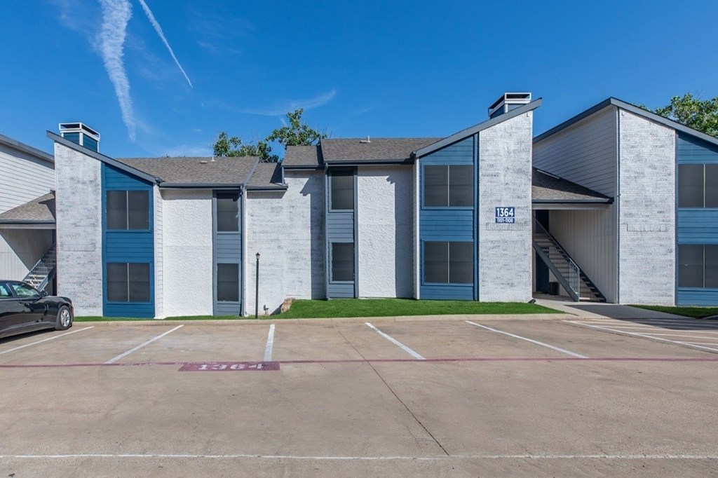 A parking lot in front of a building with a car parked in it.