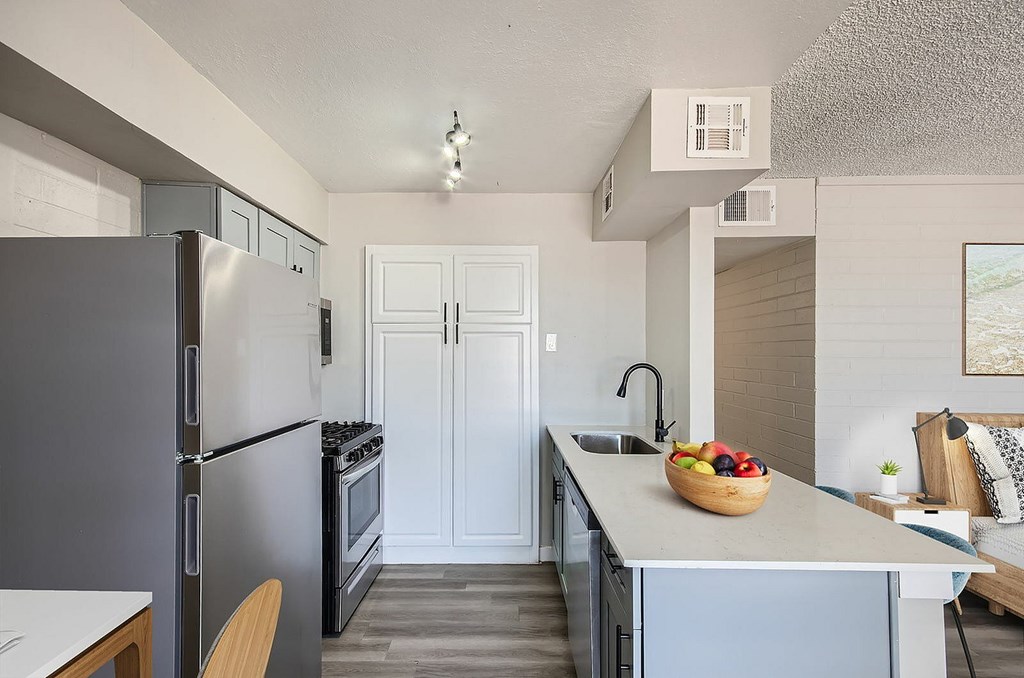 A kitchen with a refrigerator, oven, and sink.
