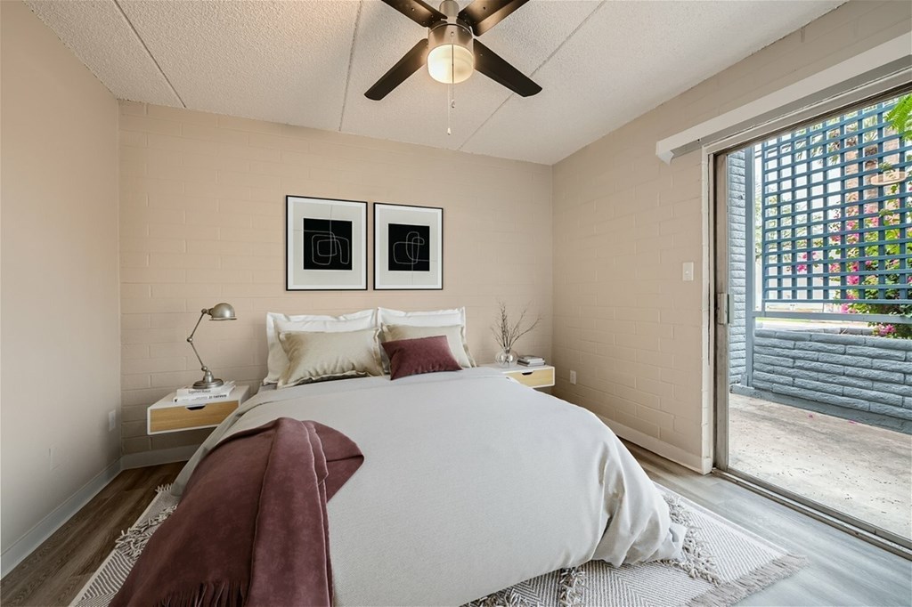 A bedroom with a bed, a ceiling fan, and two picture frames on the wall.