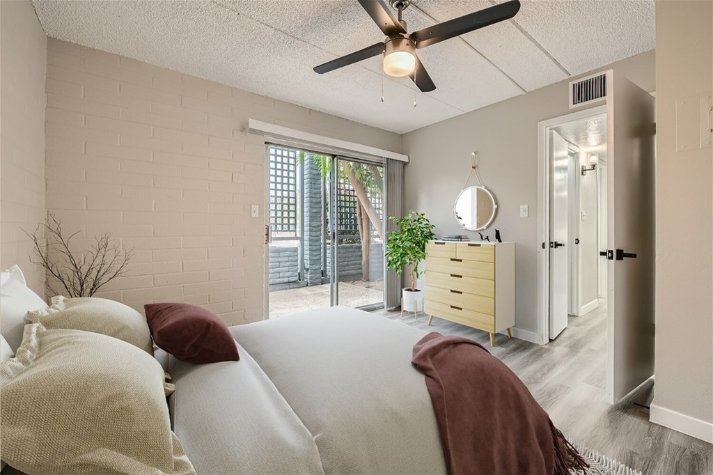 A bedroom with a bed, dresser, mirror, and a ceiling fan.