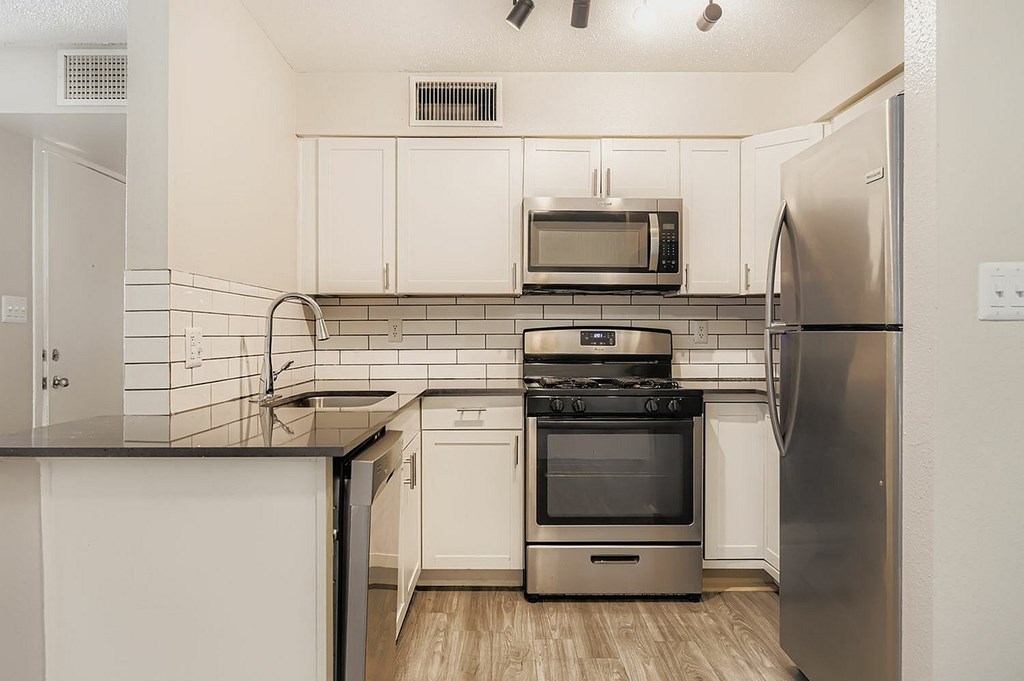 A modern kitchen with white cabinets and black countertops.