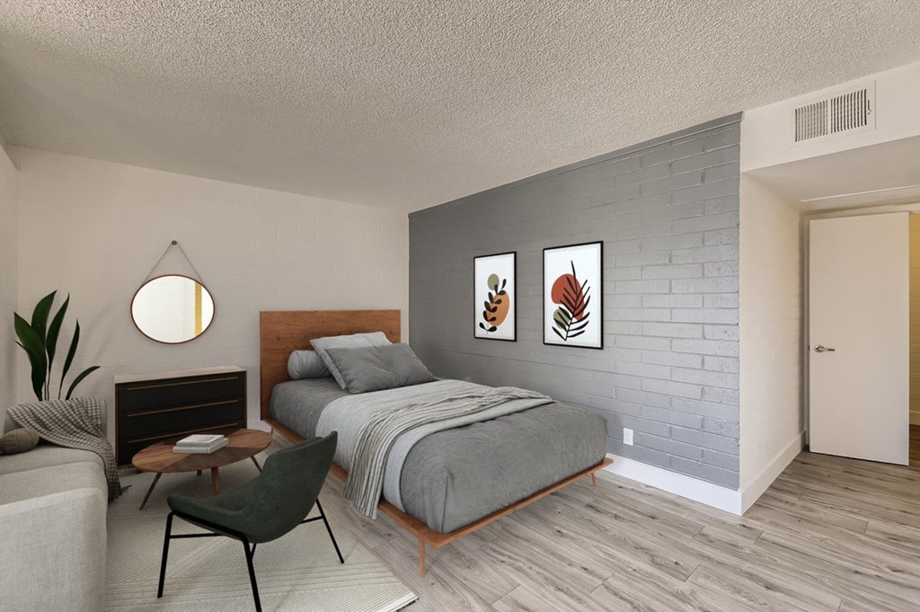 A bedroom with a bed, a chair, and a plant.