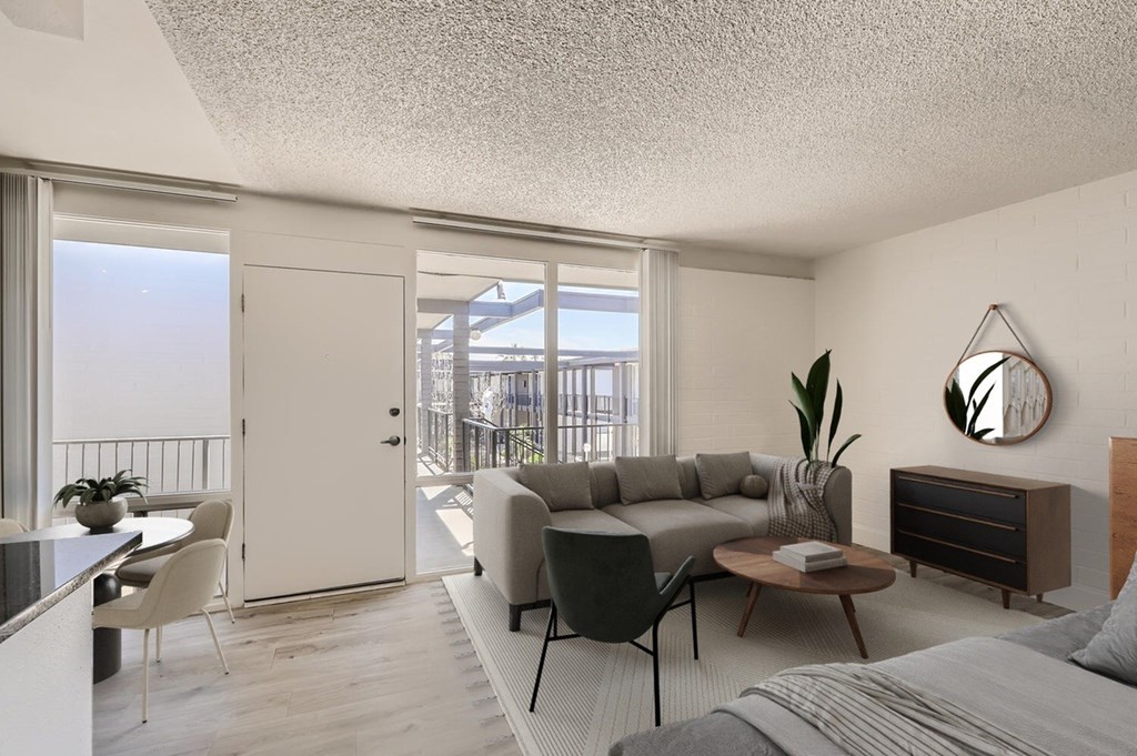 A modern living room with a grey sofa, a wooden coffee table, and a large mirror on the wall.