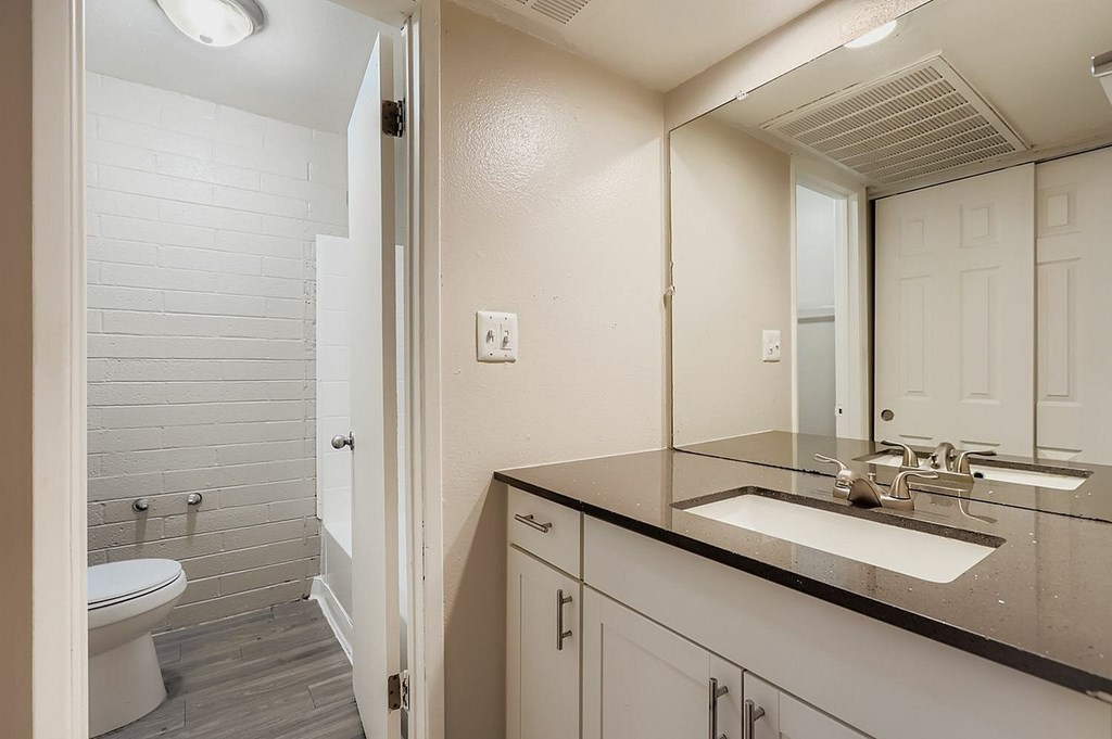 A white bathroom with a toilet, sink, and mirror.