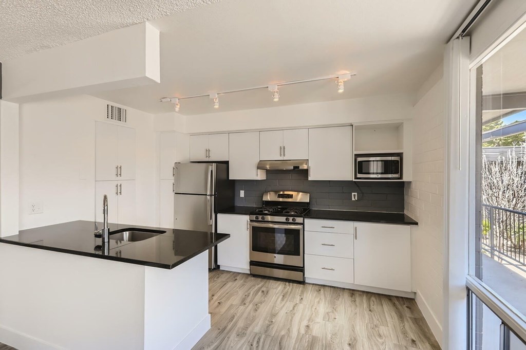 A modern kitchen with black countertops and white cabinets.