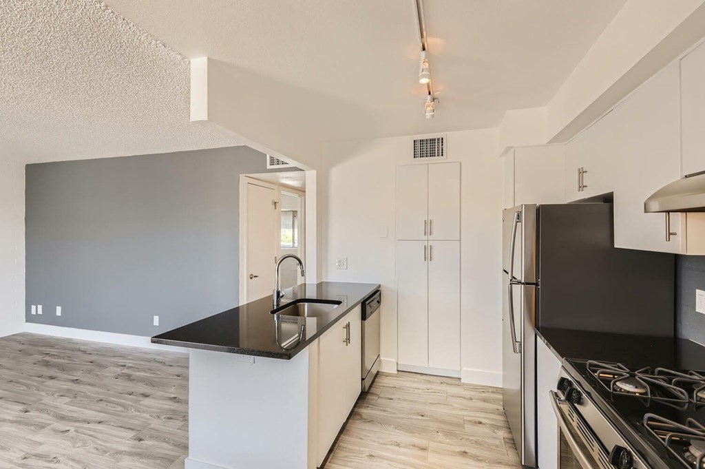 A kitchen with a black countertop and white cabinets.