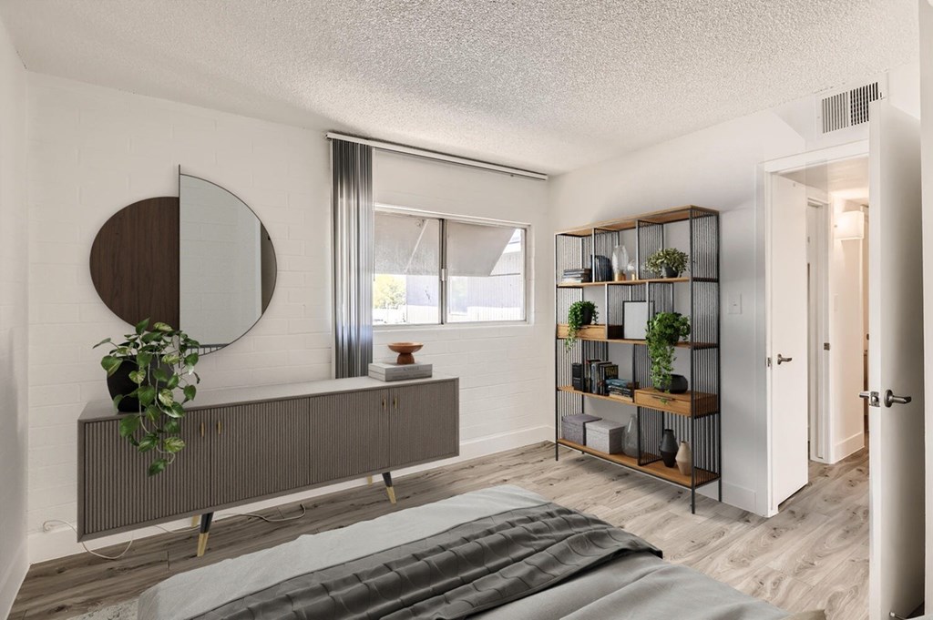 A bedroom with a bed, a mirror, and a shelf with plants.