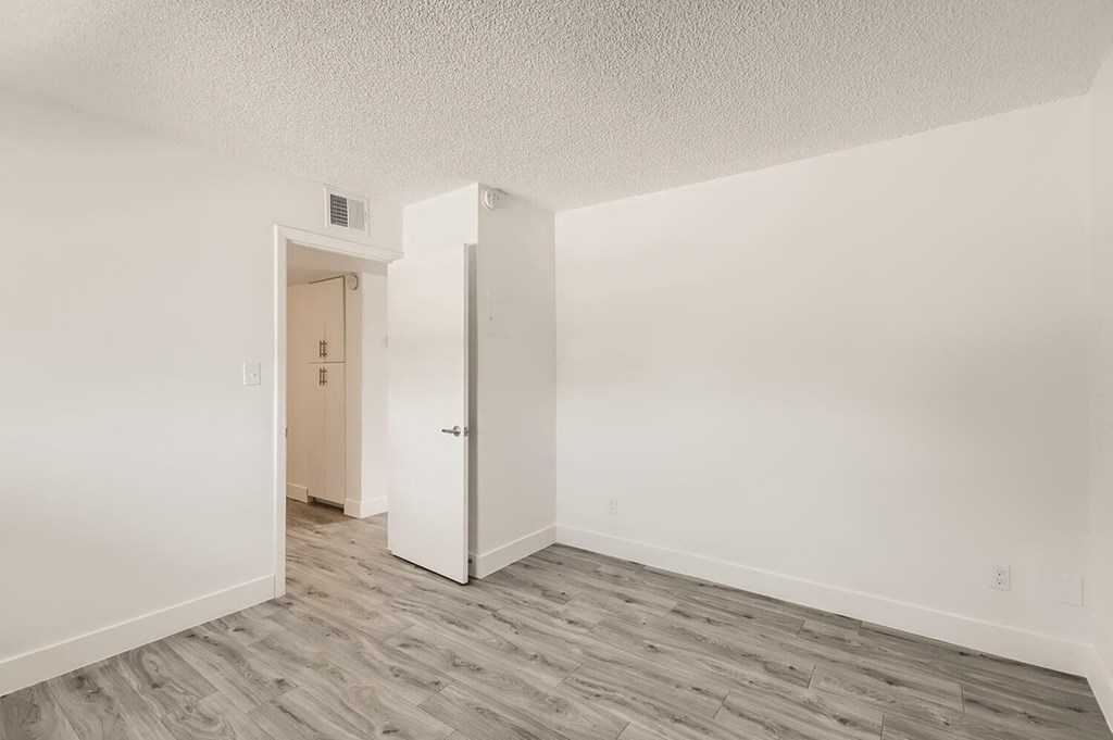 A room with a white door and a grey floor.