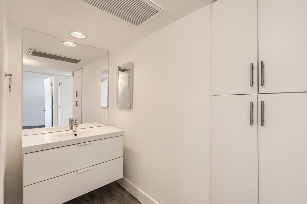 A white bathroom with a sink and a mirror.
