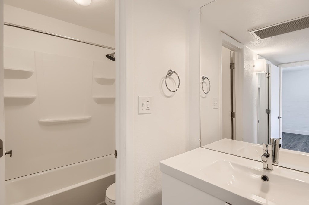 A white bathroom with a toilet, sink, and mirror.