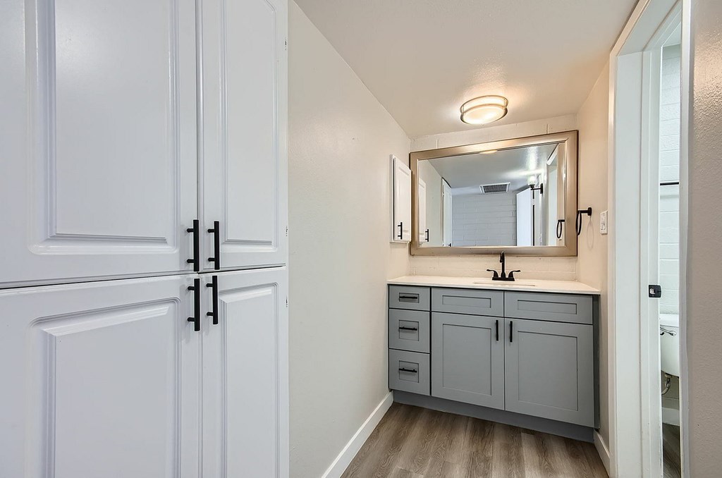 A bathroom with a white cabinet and a mirror above it.