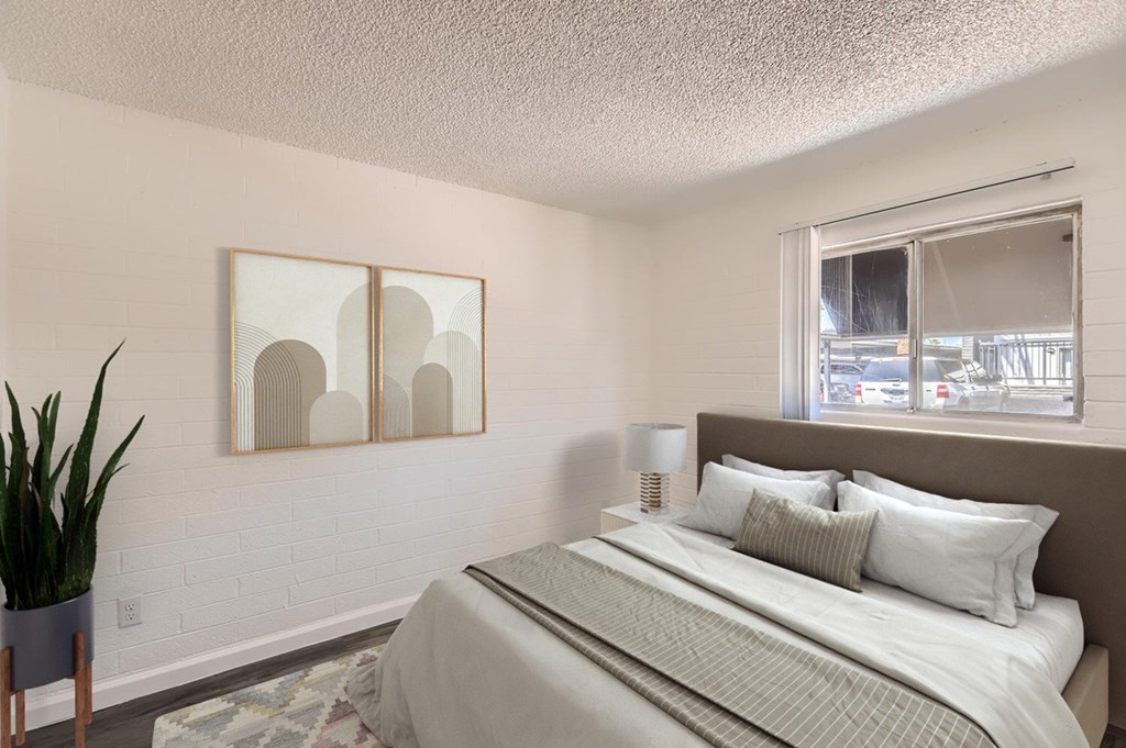 A bedroom with a large bed and a potted plant.