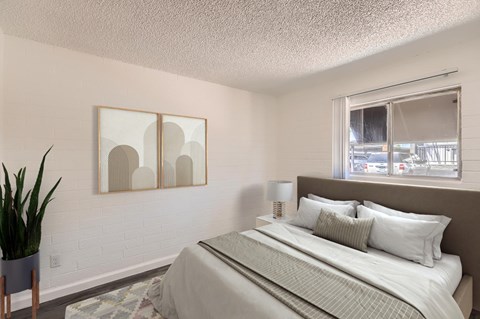 A bedroom with a large bed and a potted plant.
