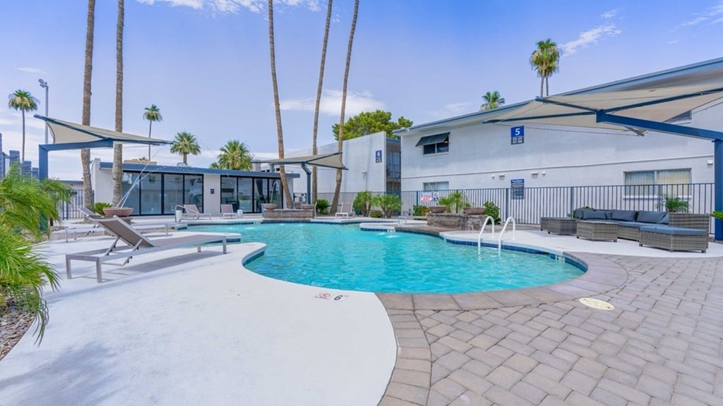 A pool with a white fence and a building in the background.