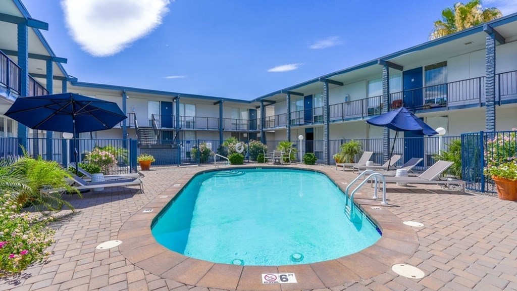 A swimming pool surrounded by a brick patio and lounge chairs.