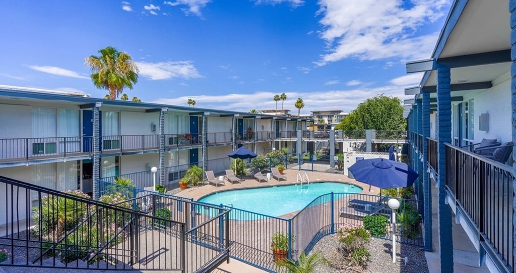 A pool surrounded by a fence and a building in the background.