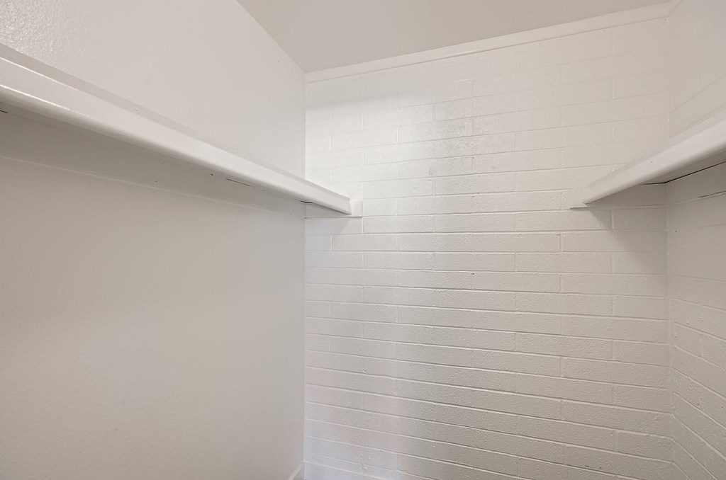 A white tiled wall with a white shelf above it.