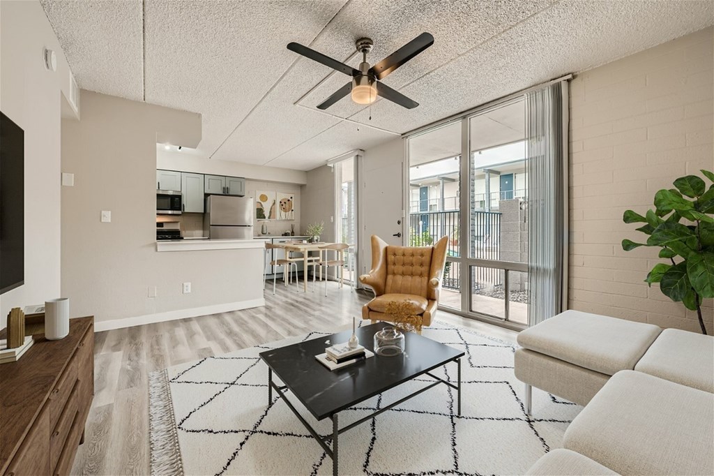 A living room with a ceiling fan and a black coffee table.