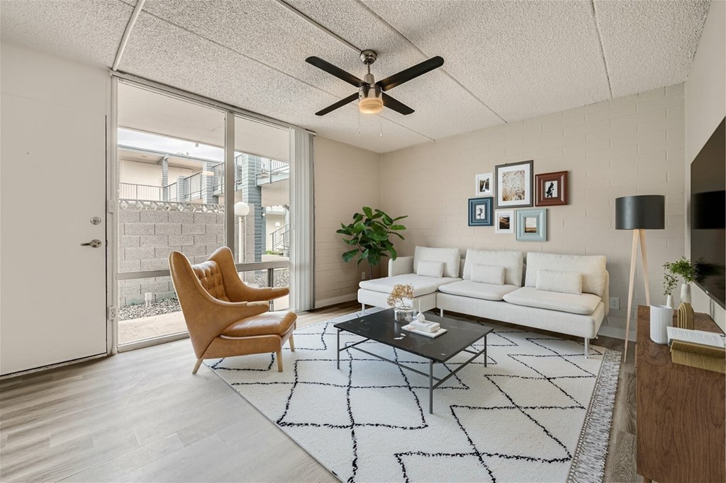 A living room with a white couch, a coffee table, and a ceiling fan.