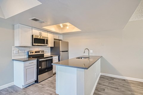 A kitchen with white cabinets and a stainless steel refrigerator.