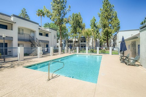 A swimming pool surrounded by a fence and trees.