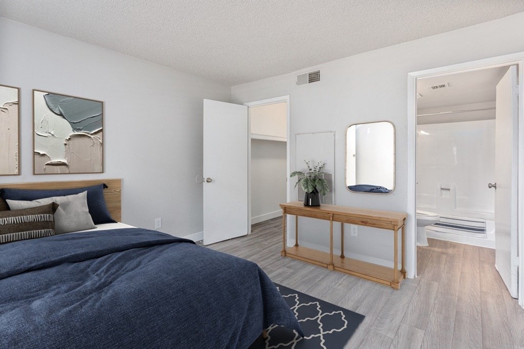 A bedroom with a bed, mirror, and wooden bench.