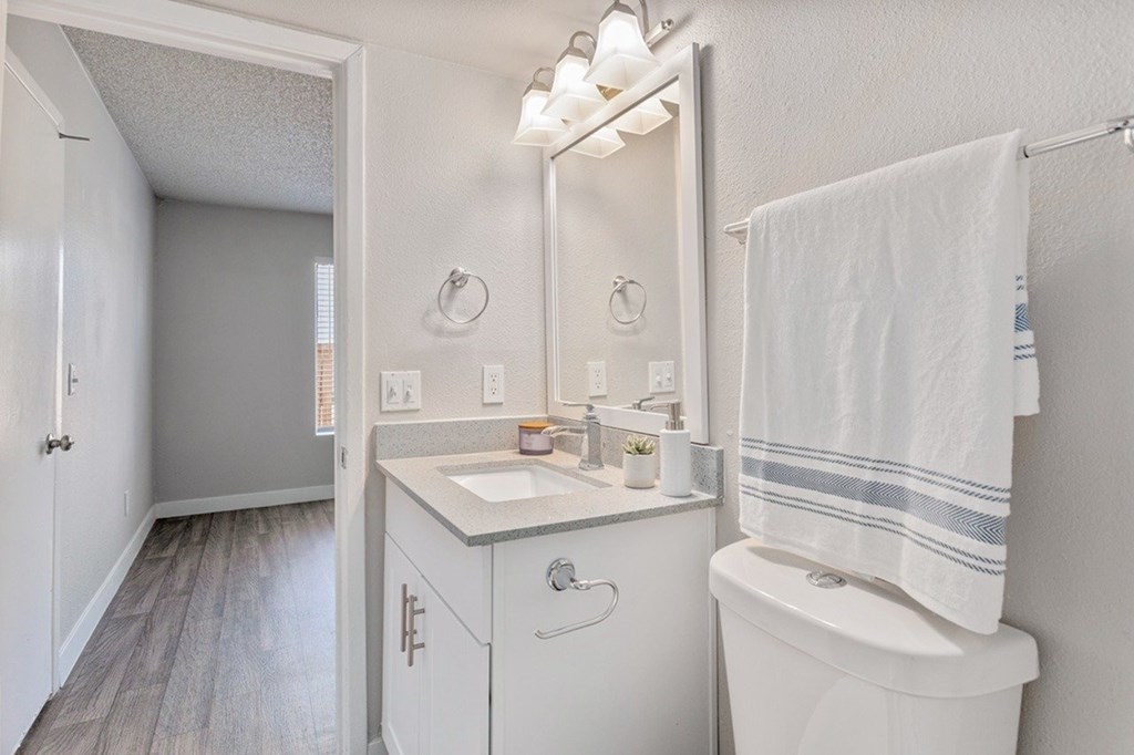 A white bathroom with a sink, toilet, and a mirror.