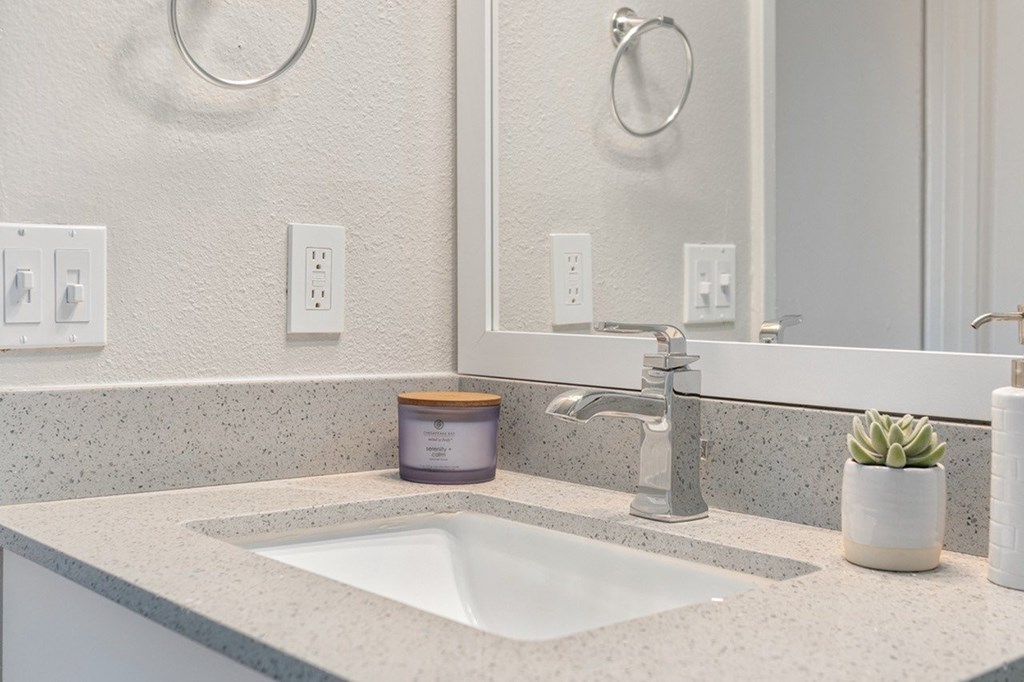 A bathroom sink with a grey faucet and a mirror above it.