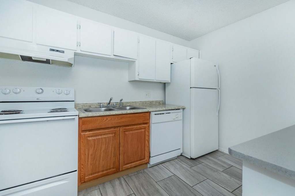 A kitchen with white appliances and wooden cabinets.